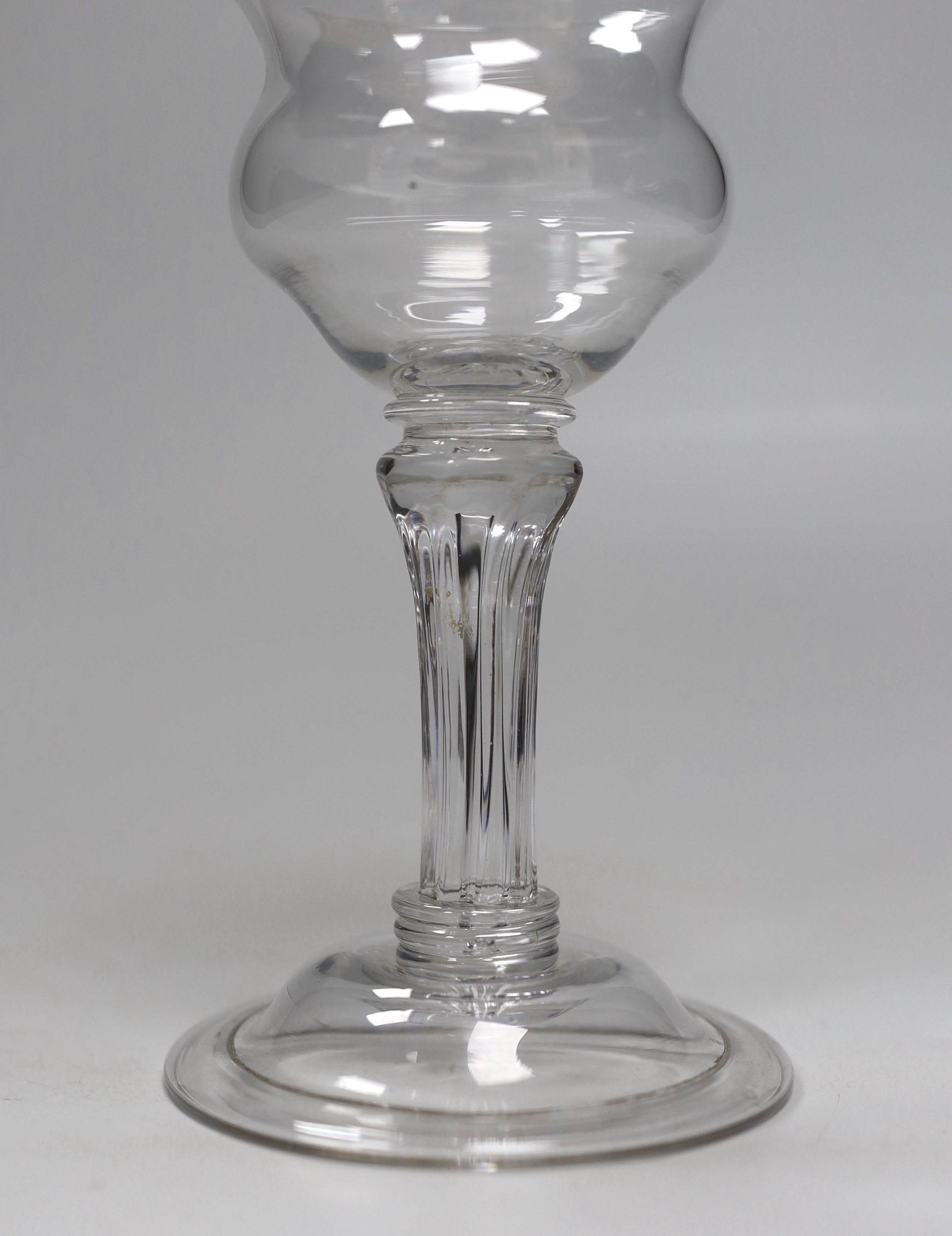 An English lead crystal champagne or sweetmeat glass c.1740, with double ogee bowl, with collar under the bowl, over a twelve sided debased, moulded pedestal stem over two collars at the base, with domed, folded foot and